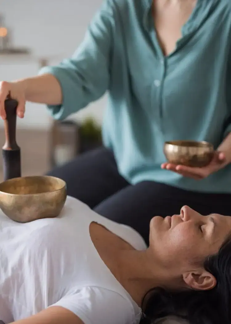 Woman undergoing sound healing with Tibetan singing bowls for holistic wellness and natural vibrational therapy