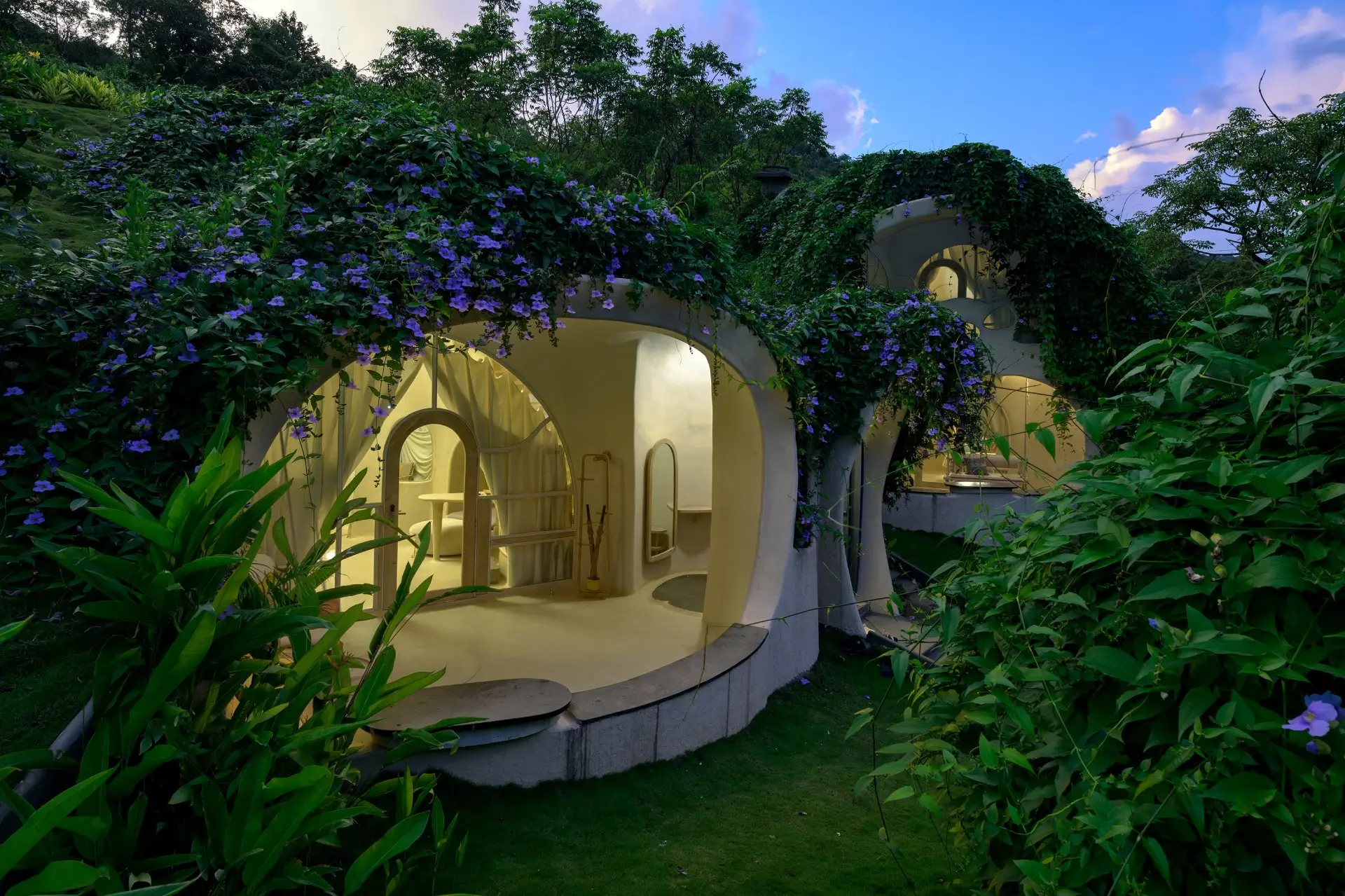 Kutumb Guha family villa at Sukh Vihar glowing at dusk amid lush greenery