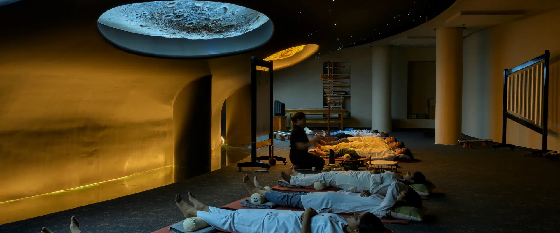 Guests in a cosmic sound healing therapy session under a starry moon-lit ceiling