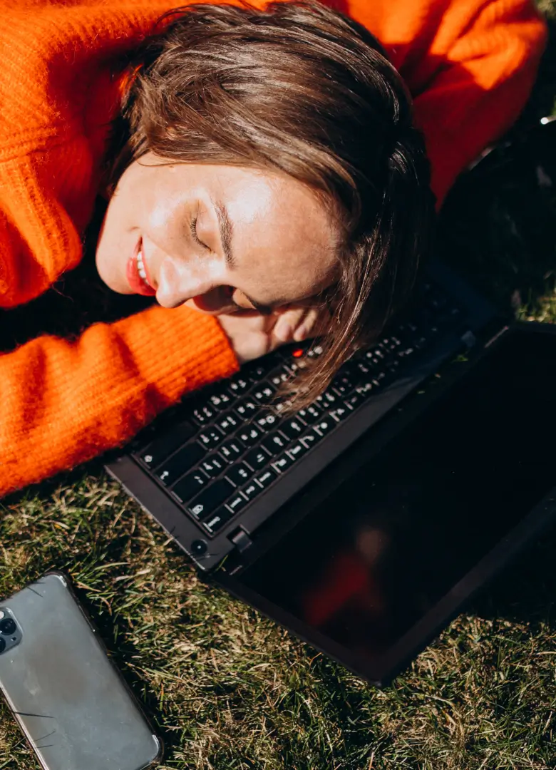 72-Hour Digital Detox_mob Woman lying on grass with her head resting on a laptop, taking a break from screens