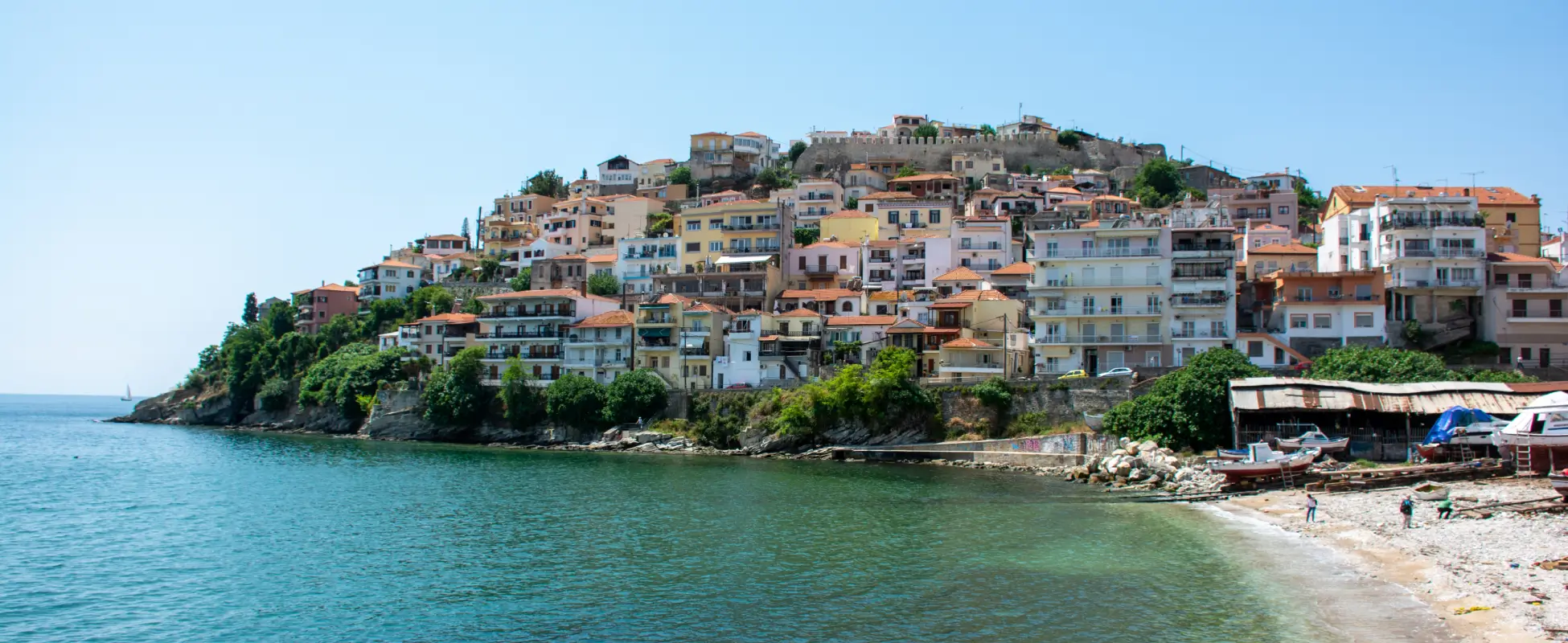 Hillside coastal town with terracotta-roofed houses above a calm turquoise bay
